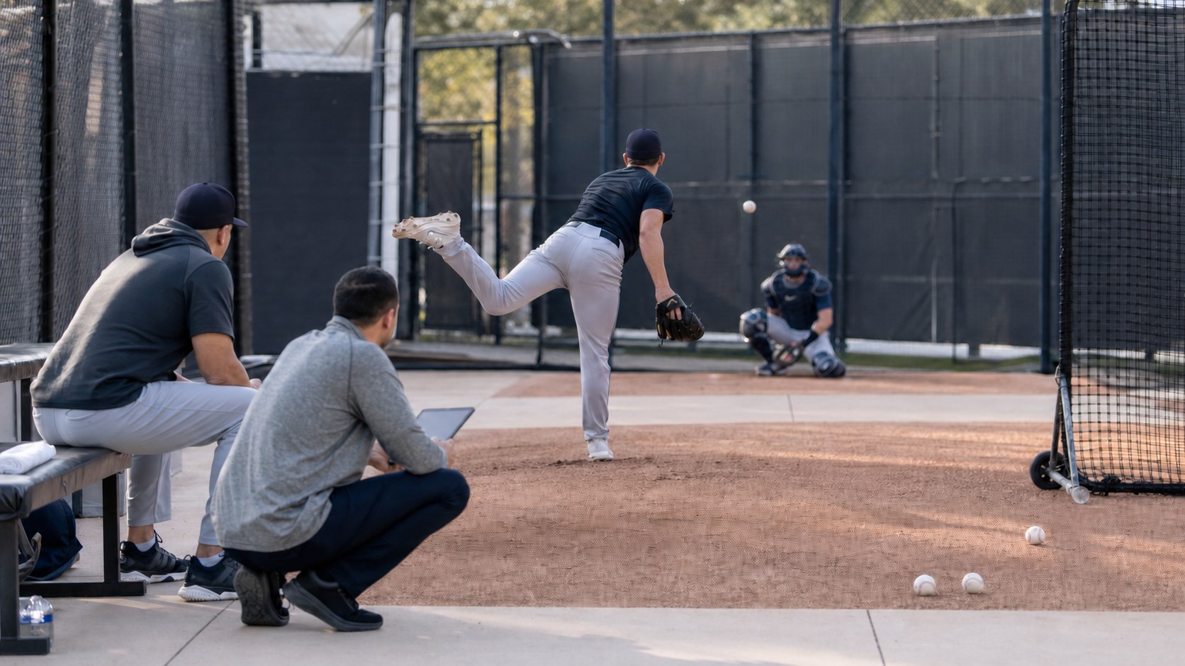 Professional pitcher completing a monitored bullpen session with coach and medical staff nearby