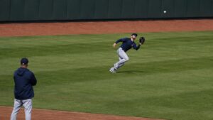 Outfielder running an efficient route toward a fly ball in deep outfield grass