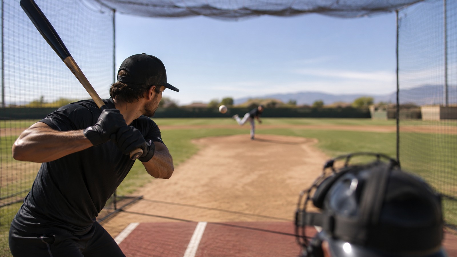 Hitter tracking an incoming pitch from inside a batting cage during focused pitch-recognition work